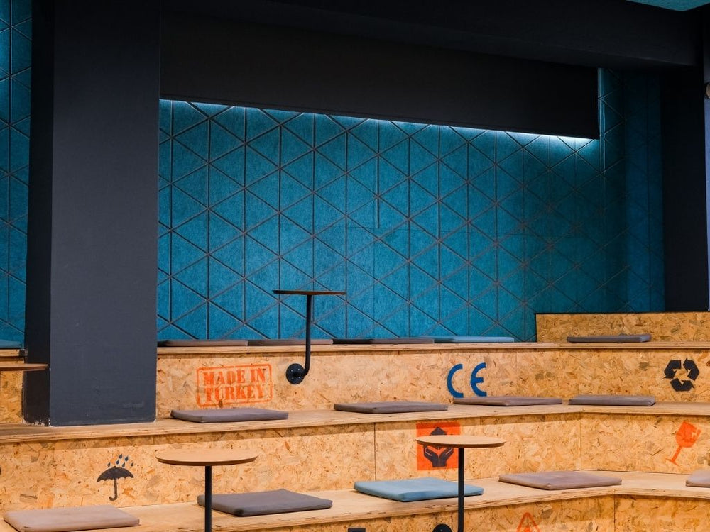 Blue geometric acoustic wall panels above tiered timber seating